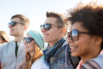 Image showing happy teenage friends in shades hugging outdoors