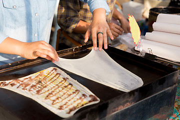Image showing close up of cook frying pancakes at street market