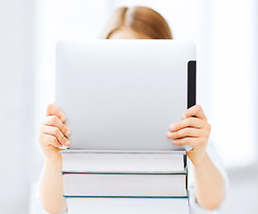 Image showing girl hiding behind tablet pc and books at school