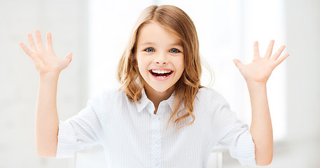 Image showing surprised and laughing girl with raised hands