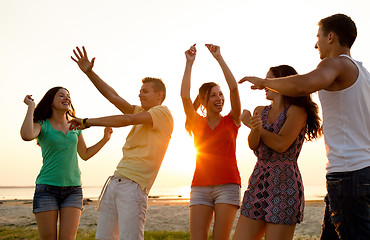 Image showing smiling friends dancing on summer beach