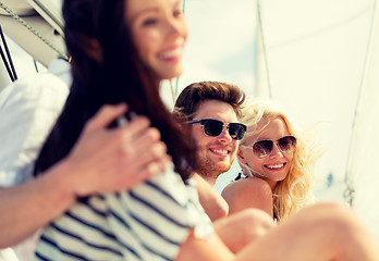 Image showing smiling friends sitting on yacht deck