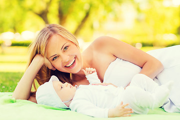 Image showing laughing mother lying with little baby on blanket