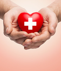 Image showing male hands holding red heart with white cross