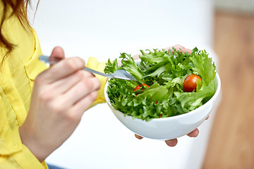 Image showing close up of young woman eating salad at home