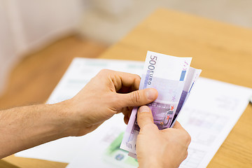 Image showing close up of man hands counting money at home