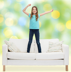 Image showing smiling little girl jumping on sofa