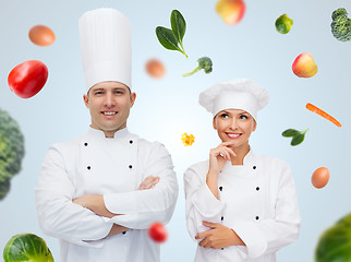 Image showing happy chef couple or cooks over food background