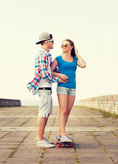 Image showing smiling couple with skateboard outdoors