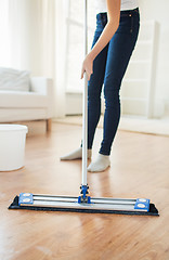 Image showing close up of woman with mop cleaning floor at home