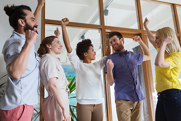 Image showing happy creative team celebrating victory in office