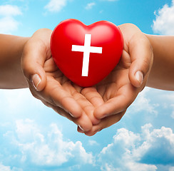 Image showing close up of hands holding heart with cross symbol