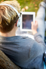Image showing close up of teenager in headphones with tablet pc