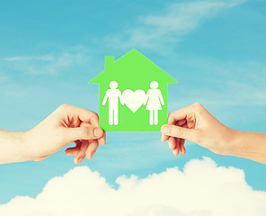 Image showing hands holding green house with family