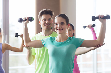 Image showing happy women and trainer with dumbbells in gym