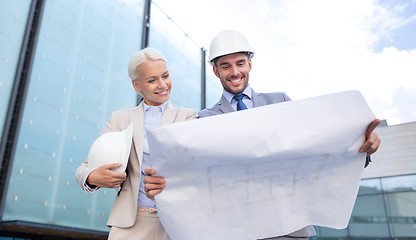 Image showing smiling businessmen with blueprint and helmets