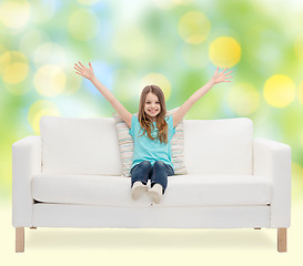 Image showing happy girl sitting on sofa with raised hands