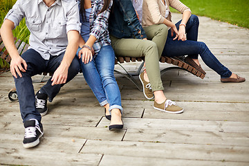 Image showing close up of many legs sitting on bench at park