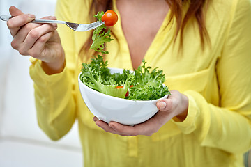 Image showing close up of young woman eating salad at home