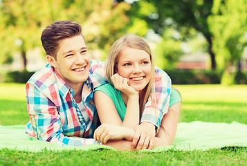 Image showing smiling couple lying on blanket in park