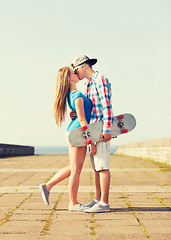 Image showing couple with skateboard kissing outdoors