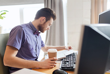 Image showing creative male worker drinking coffee and reading