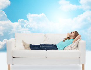 Image showing smiling little girl lying on sofa and dreaming