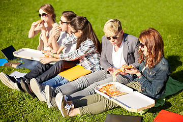 Image showing group of teenage students eating pizza on grass