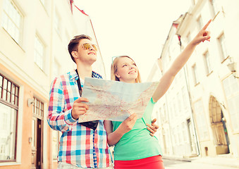 Image showing smiling couple with map and photo camera in city