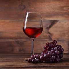 Image showing Red wine in glass with grape on wood