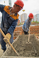 Image showing Workers knead solution for bricklayers