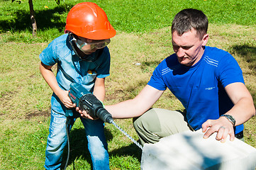 Image showing A child learns to work with electric drill