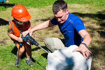 Image showing A child learns to work with electric drill