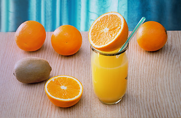 Image showing Orange juice in a glass and oranges on the table.