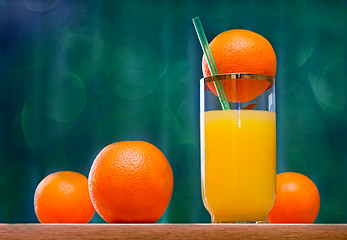 Image showing Orange juice in a glass and oranges on the table.