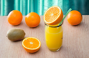 Image showing Orange juice in a glass and oranges on the table.