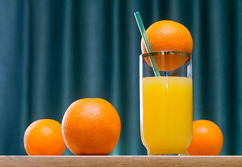 Image showing Orange juice in a glass and oranges on the table.