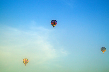 Image showing three hot air balloons flying above morning fog