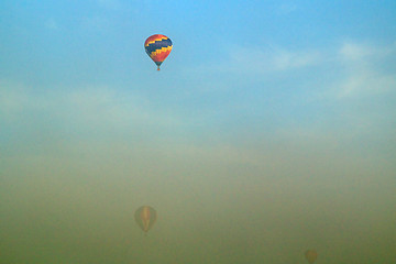 Image showing three hot air balloons flying through morning fog