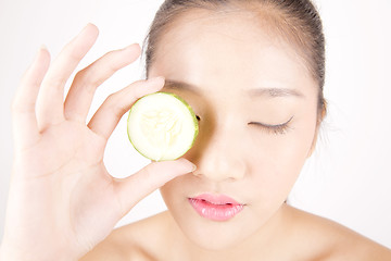 Image showing Beautiful young Asian girl holding cucumber slice over face