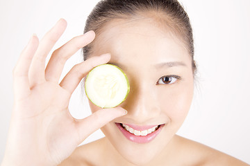 Image showing Beautiful young Asian girl holding cucumber slice over face