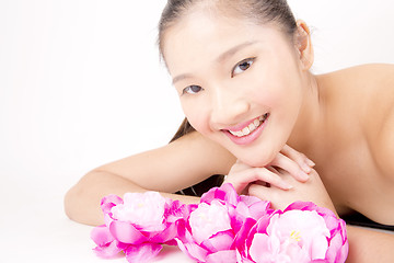Image showing Beautiful young Asian girl lying down with red peony flowers