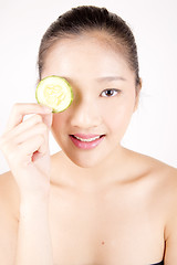 Image showing Beautiful young Asian girl holding cucumber slice over face