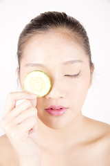 Image showing Beautiful young Asian girl holding cucumber slice over face