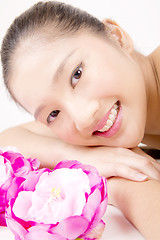 Image showing Beautiful young Asian girl lying down with red peony flowers