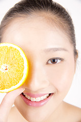 Image showing Beautiful young Asian girl holding orange slice over face