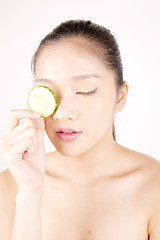 Image showing Beautiful young Asian girl holding cucumber slice over face