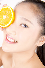 Image showing Beautiful young Asian girl holding orange slice over face