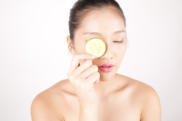 Image showing Beautiful young Asian girl holding cucumber slice over face