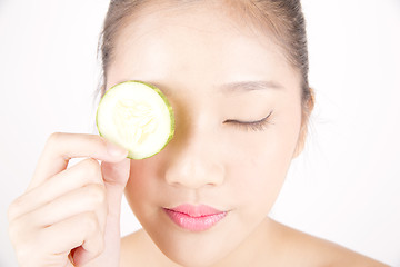 Image showing Beautiful young Asian girl holding cucumber slice over face